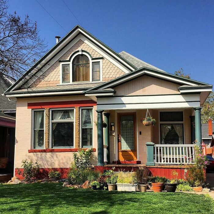 Charming old home with a front porch, colorful trim, and well-maintained garden under clear blue sky.