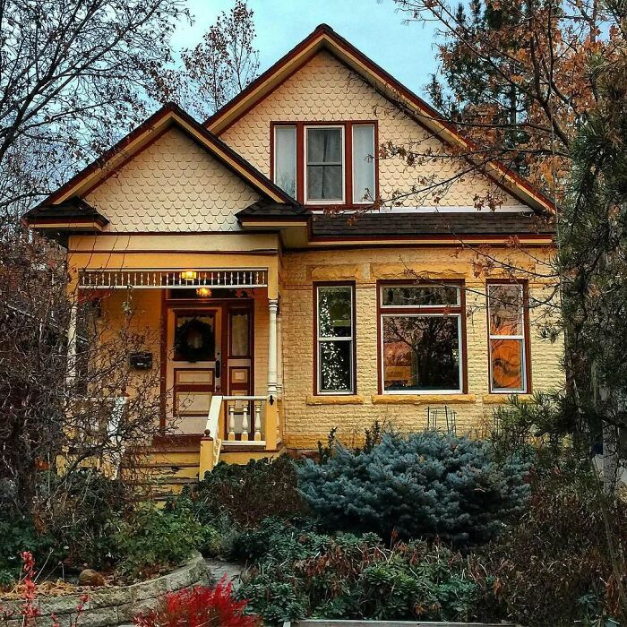 Lovely old home with yellow exterior, gabled roof, and autumn trees surrounding the charming front yard and porch entrance