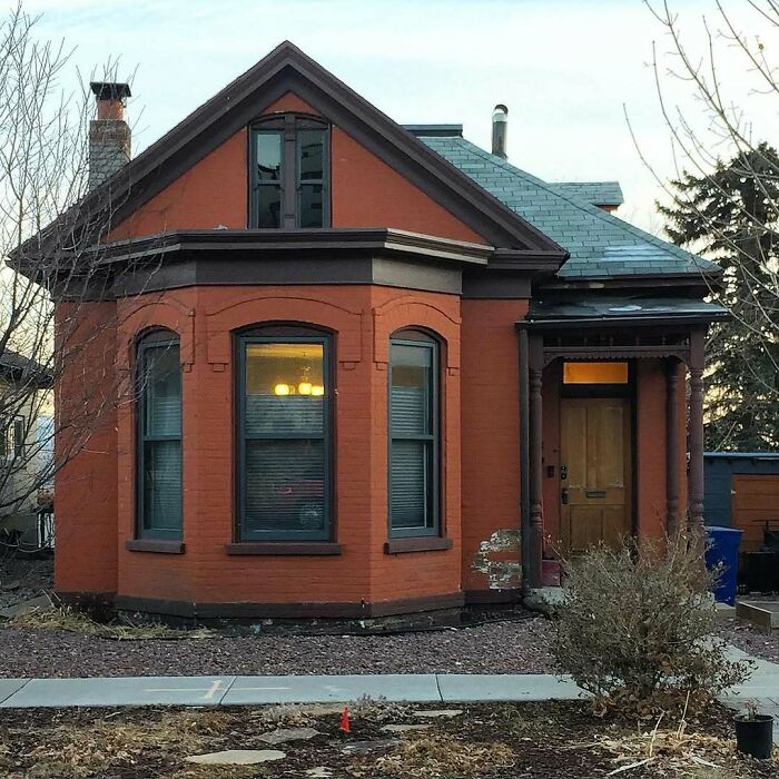 Charming old home with red brick exterior, bay windows, and vintage architectural details in a quiet neighborhood setting.