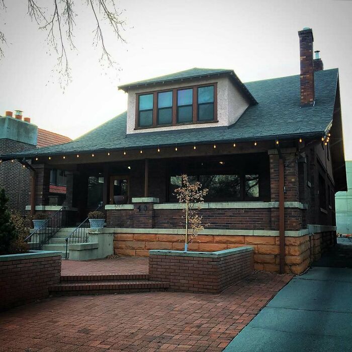 Adorable old home with brick exterior and large porch, showcasing charming architecture and inviting outdoor space.