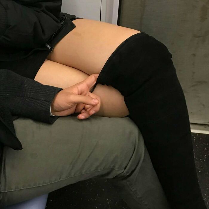 Person sitting on the subway in New York with a hand gesture resting on a thigh wearing black thigh-high boots.