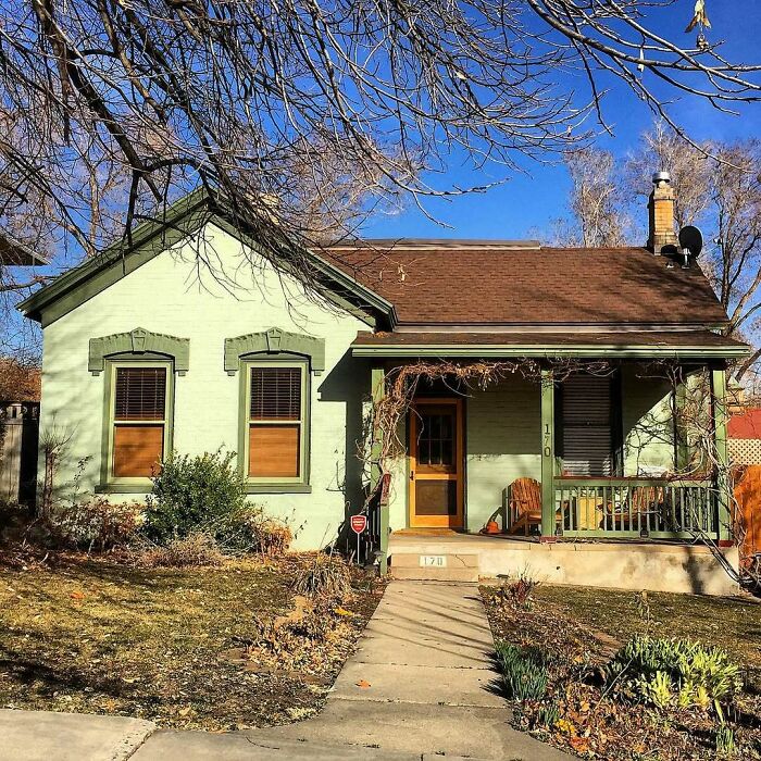 Charming old home with green trim and porch, surrounded by trees, perfect for those seeking adorable lovely old homes to move into.