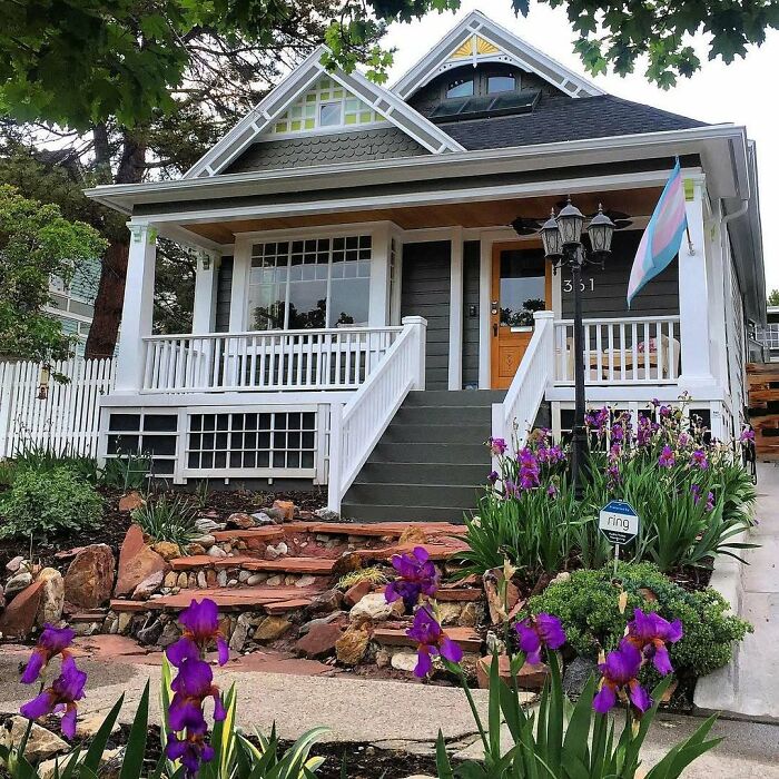 Charming old home with a welcoming porch and vibrant purple flowers in the front yard, perfect for lovely old homes.
