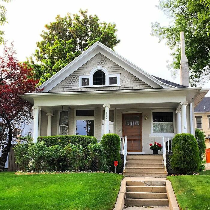 Charming old home with front porch surrounded by lush greenery and trees, inviting for a cozy and lovely living experience.