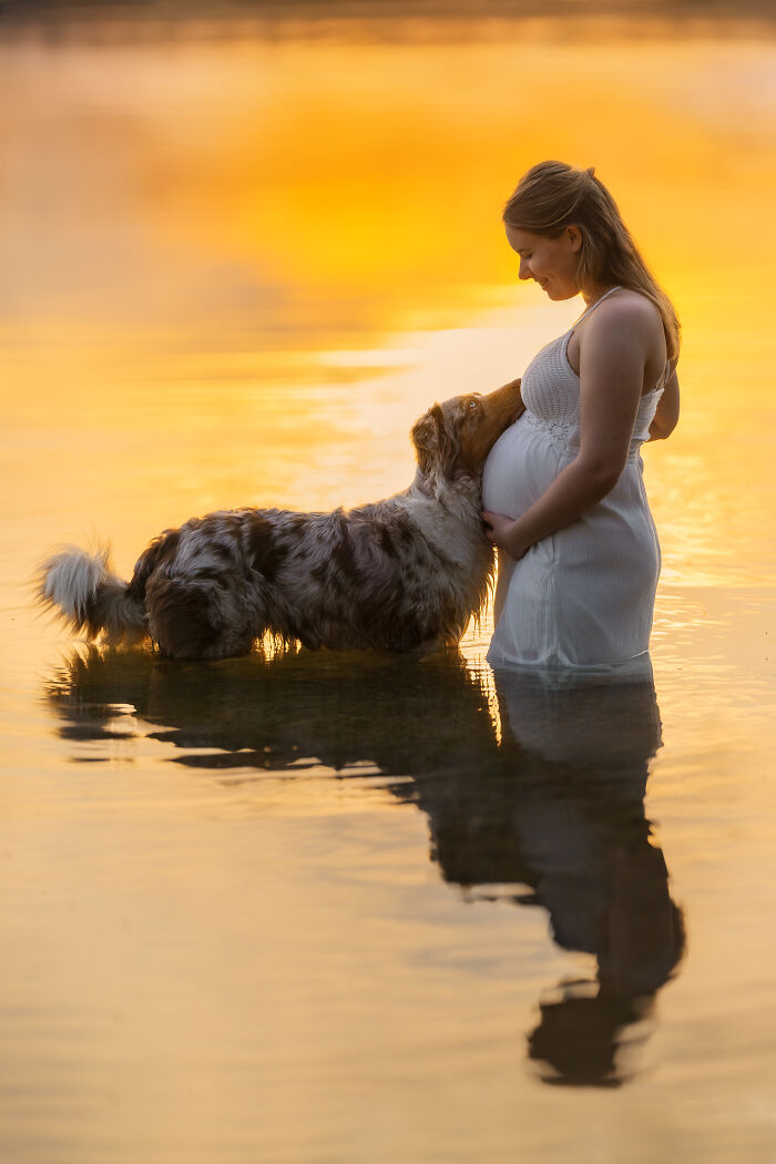 Woman lying on sand embracing her dog in a heartwarming pet photo from the 2025 International Pet Photography Awards.