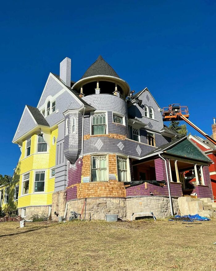 Colorful old home with unique architectural details under a clear blue sky, showcasing charming vintage charm.