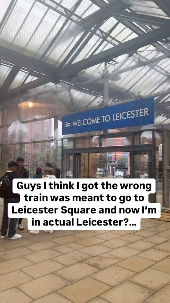 Group of people standing under a Welcome to Leicester sign, mistaken train ride instead of London meme humor.
