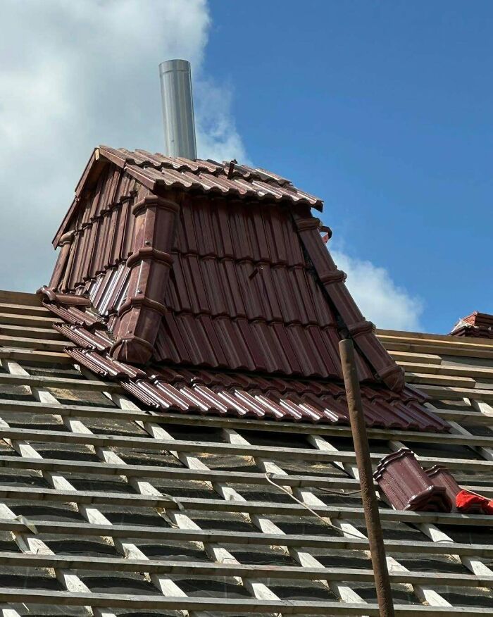 Roof construction with poorly executed tile design creating an awkward and uneven structure under clear blue sky.