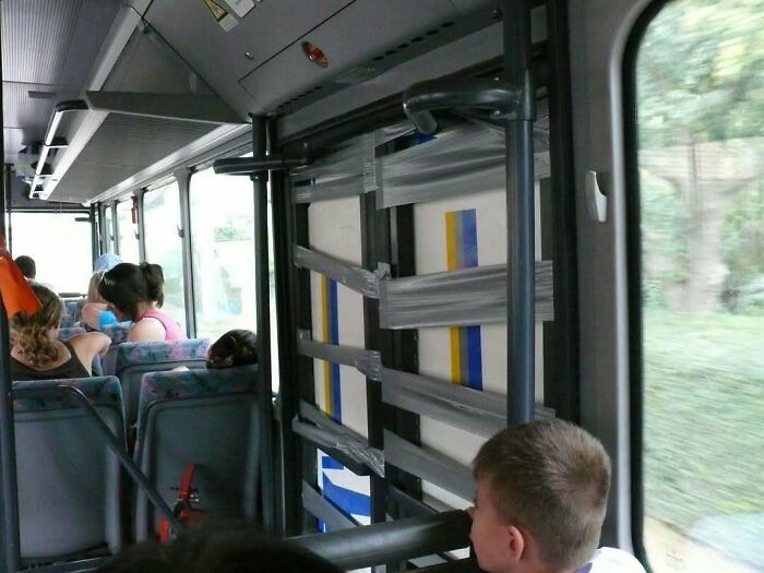 Bus interior with poorly designed handrails obstructing the window, an example of construction and designs with flawed usability.