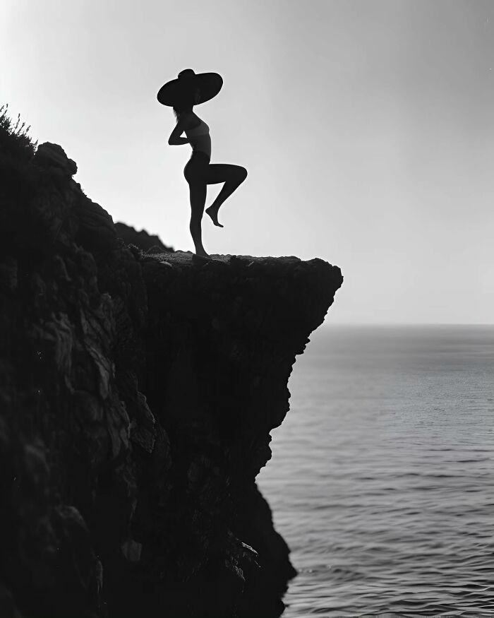 Silhouette of a woman in a wide hat standing on a cliff by the ocean, a dreamy minimalist photo of peaceful escape.