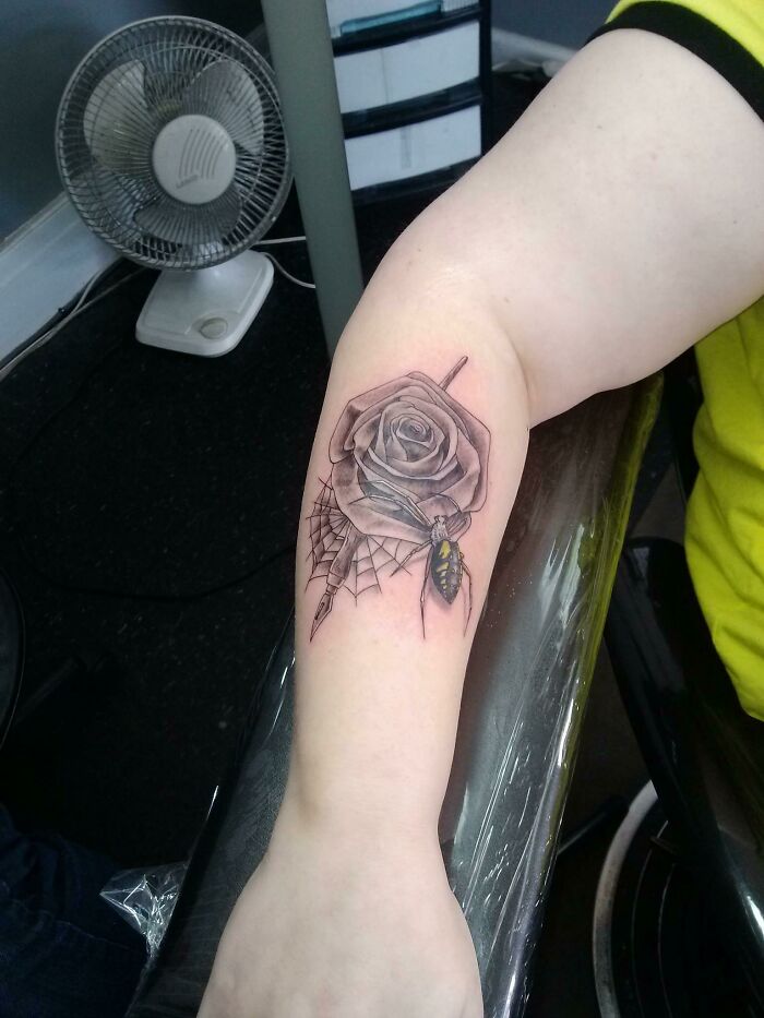 Tattoo artist’s work showing a rose with a spider and web inked on person's inner forearm.
