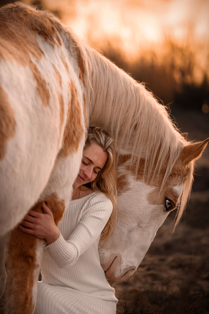 Woman running alongside a rearing horse in a flower-filled field, capturing creative pet photos with heartwarming energy.