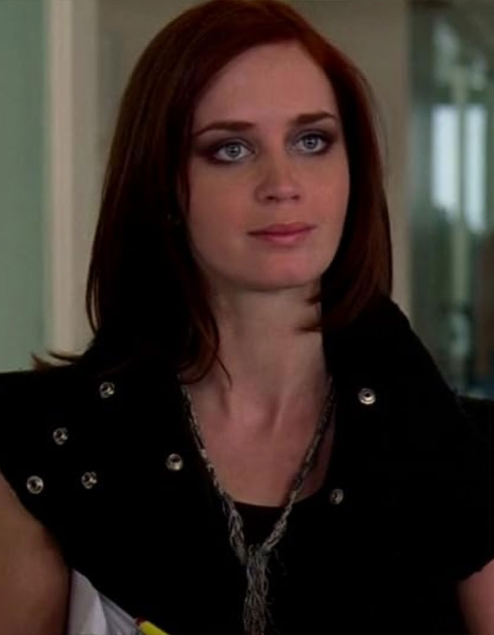 Emily Blunt with red hair and smoky eye makeup, wearing a black studded outfit indoors. Emily Blunt with red hair and smoky eye makeup, wearing a black studded outfit indoors.