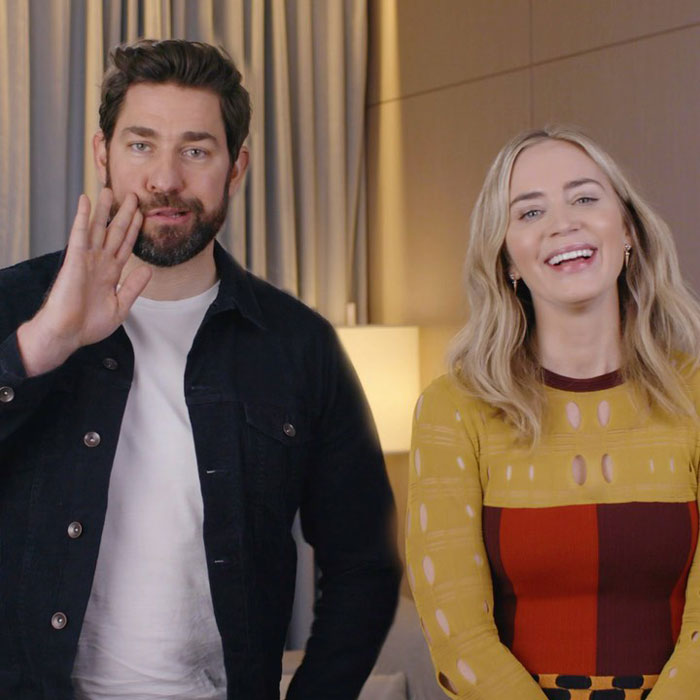Man with beard waving hand next to smiling woman in colorful dress, related to Emily Blunt braless look plastic surgery rumors. Man with beard waving hand next to smiling woman in colorful dress, related to Emily Blunt braless look plastic surgery rumors.