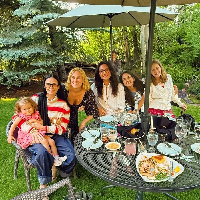 Bruce Willis wife with family outdoors at a garden table, defending decision amid dementia battle. Bruce Willis wife with family outdoors at a garden table, defending decision amid dementia battle.