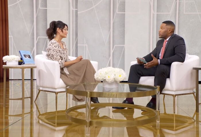 Woman and man sitting in white chairs having a discussion in a studio about Bruce Willis' wife defending dementia move decision. Woman and man sitting in white chairs having a discussion in a studio about Bruce Willis' wife defending dementia move decision.