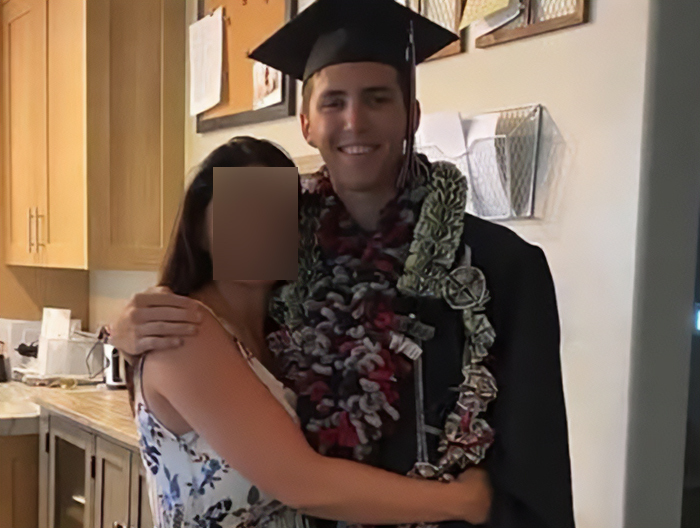 Young man in graduation robe and cap with floral leis hugging a woman in a kitchen, related to Michigan church tragedy and Charlie Kirk attack. Young man in graduation robe and cap with floral leis hugging a woman in a kitchen, related to Michigan church tragedy and Charlie Kirk attack.