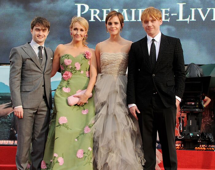 J.K. Rowling with Emma Watson and Harry Potter cast at a film premiere event dressed in formal attire. J.K. Rowling with Emma Watson and Harry Potter cast at a film premiere event dressed in formal attire.