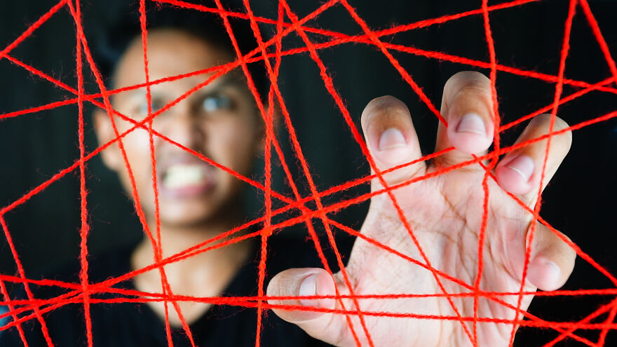 Person interacting with red strings symbolizing invisible string theory in modern romance and the role of destiny. Person interacting with red strings symbolizing invisible string theory in modern romance and the role of destiny.
