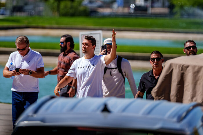 Group of men outdoors with one raising a hand, unrelated to Charlie Kirk sniper’s rooftop nest eerie photos perspective. Group of men outdoors with one raising a hand, unrelated to Charlie Kirk sniper’s rooftop nest eerie photos perspective.