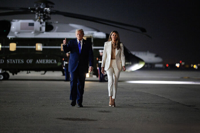 Donald Trump and Melania walking near helicopter at night, with body language experts analyzing finger-pointing interaction. Donald Trump and Melania walking near helicopter at night, with body language experts analyzing finger-pointing interaction.