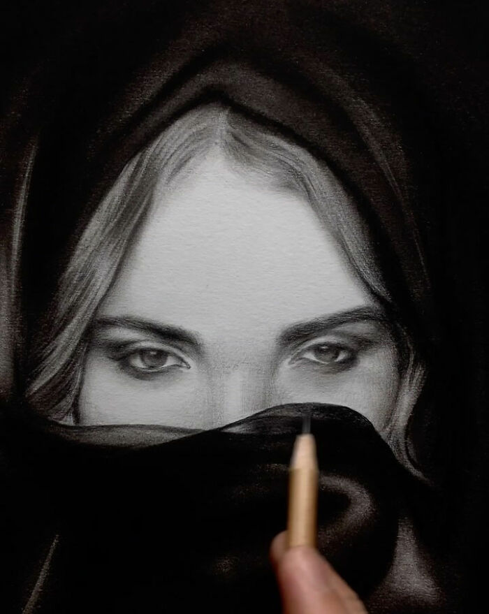 Hand drawing an incredible pencil portrait of a woman's detailed eyes partially covered by a dark fabric.