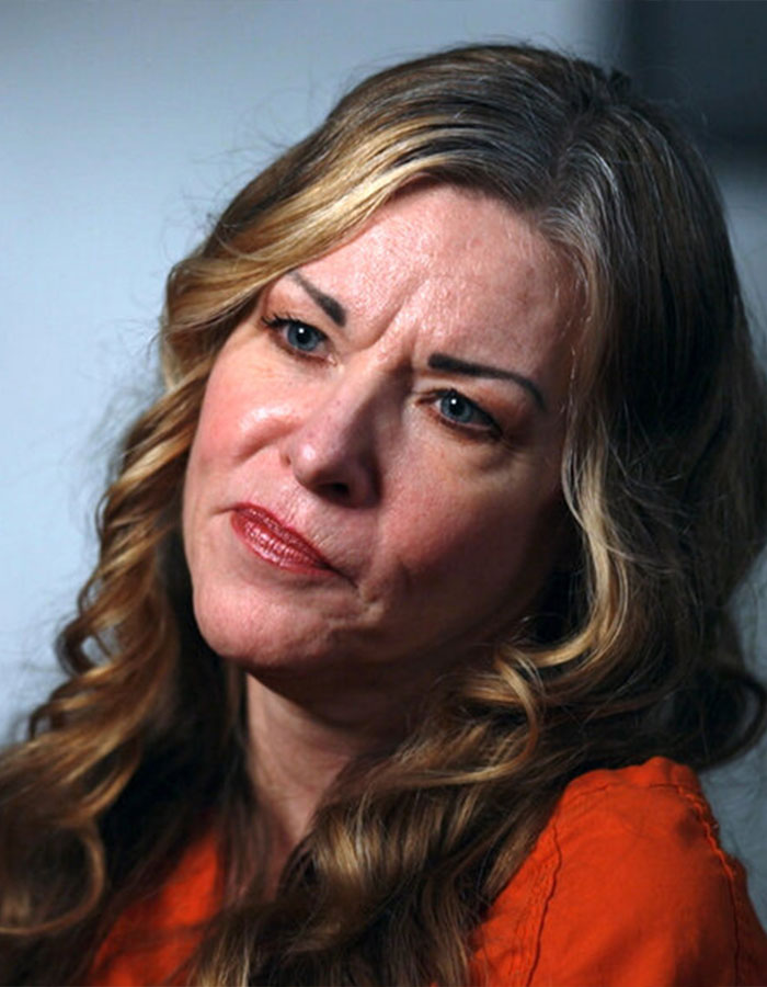 Convicted doomsday cult mom with curled blonde hair and orange top, sending a creepy message at CrimeCon event. Convicted doomsday cult mom with curled blonde hair and orange top, sending a creepy message at CrimeCon event.