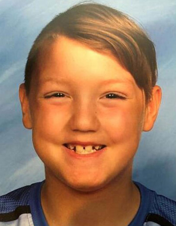 Smiling young boy with missing front teeth in a blue shirt, representing surviving son in doomsday cult story. Smiling young boy with missing front teeth in a blue shirt, representing surviving son in doomsday cult story.