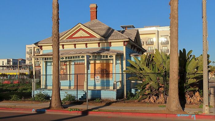 Blue Victorian-style house with a front porch behind a fence, an example of iconic TV houses existing in real life.