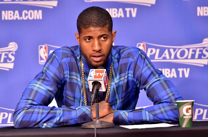Paul George at a press conference, wearing a blue plaid shirt, representing highest paid athletes in 2025.