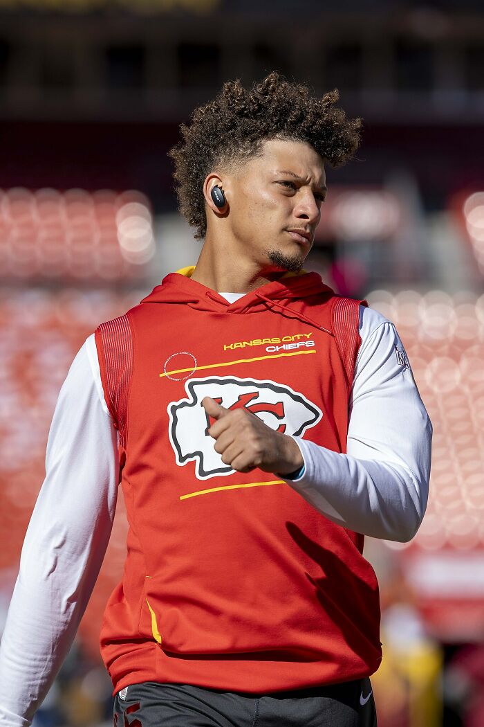 Athlete in Kansas City Chiefs gear warming up with earbuds, representing highest paid athletes of 2025.