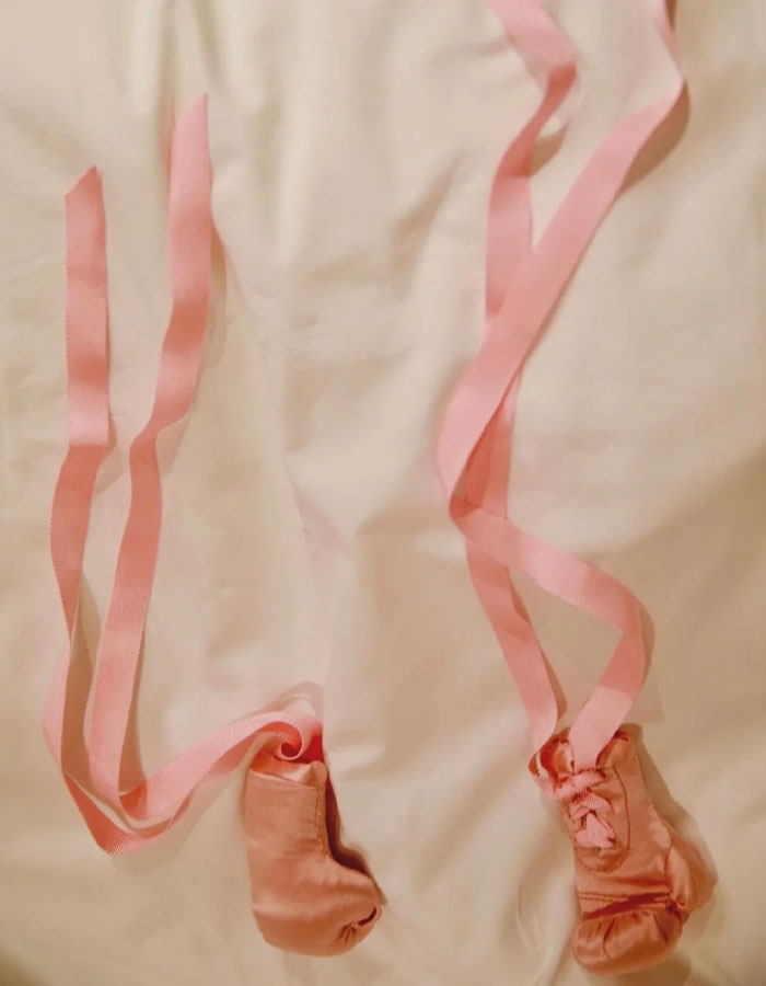 Pink baby boxing gloves with long ribbons placed on a light fabric background symbolizing Rihanna fans urging name change. Pink baby boxing gloves with long ribbons placed on a light fabric background symbolizing Rihanna fans urging name change.
