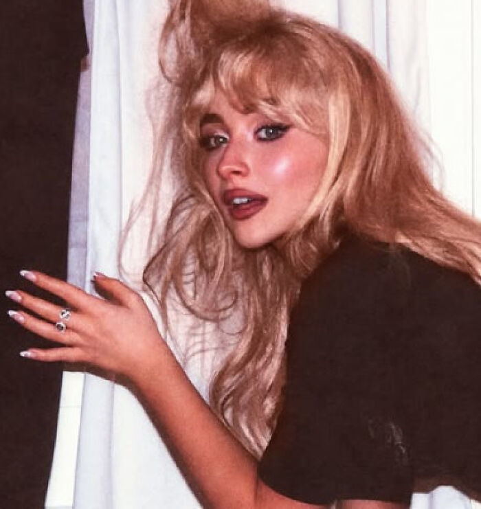 Young woman with tousled blonde hair and dark makeup posing indoors, related to kaomojis cultural appropriation discussion.