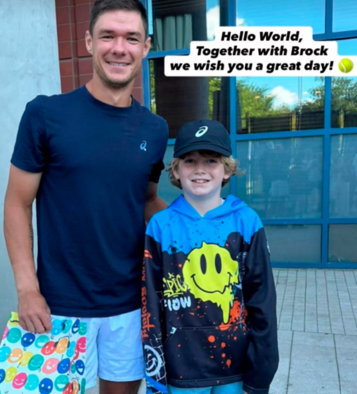 Man in navy shirt and boy in smiley face hoodie posing outside, related to disgraced CEO who snatched boy's cap at US Open. Man in navy shirt and boy in smiley face hoodie posing outside, related to disgraced CEO who snatched boy's cap at US Open.