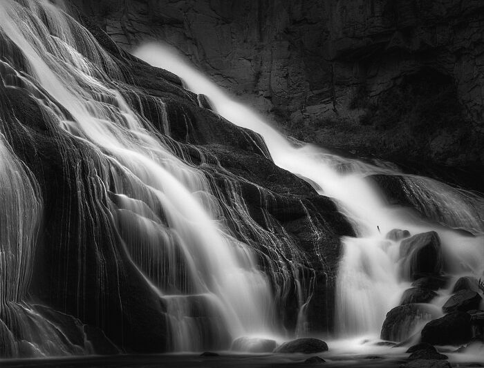 Black and white analog photo of a cascading waterfall over rugged rocks featured in Analog Sparks Awards.