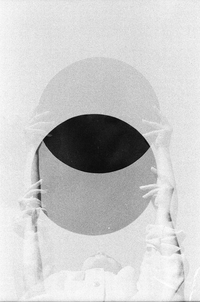 Abstract analog photo showing hands holding a dark circle in a grainy black and white film image at Analog Sparks Awards.