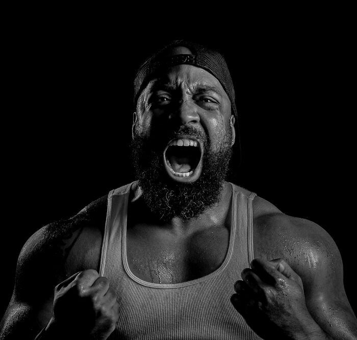 Muscular bearded man in a tank top shouting fiercely, representing the bold spirit of toddlers or alligator poll challenge.