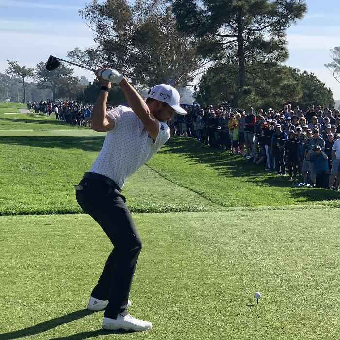 Professional golfer swinging a club on a lush golf course with a large crowd watching, showcasing highest paid athletes.