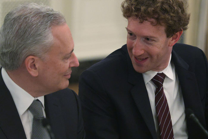 Mark Zuckerberg and a man in suits sharing a moment during a meeting, highlighting a hot mic incident with Donald Trump. Mark Zuckerberg and a man in suits sharing a moment during a meeting, highlighting a hot mic incident with Donald Trump.
