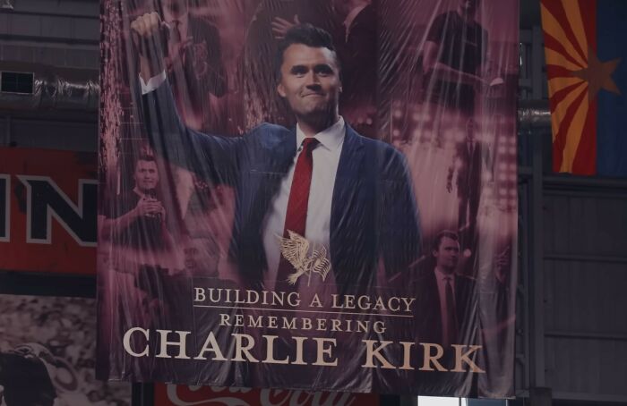 Banner displaying Charlie Kirk raising his fist, symbolizing legacy and related to Erika Kirk's gesture during husband's funeral viral moment. Banner displaying Charlie Kirk raising his fist, symbolizing legacy and related to Erika Kirk's gesture during husband's funeral viral moment.
