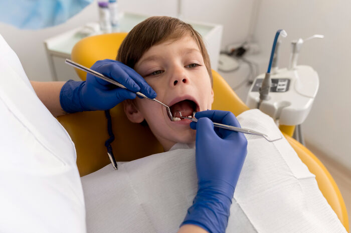 Young boy in dental chair receiving checkup from dentist wearing blue gloves, highlighting dentist discrimination against autistic kid. Young boy in dental chair receiving checkup from dentist wearing blue gloves, highlighting dentist discrimination against autistic kid.