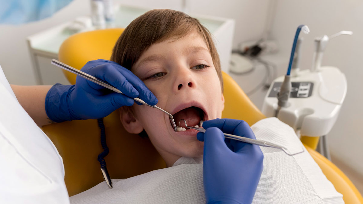 Young boy receiving dental exam from dentist wearing blue gloves in a clinic setting focused on autism discrimination concerns