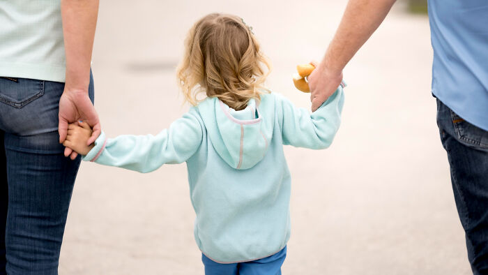 Child holding hands with two adults, symbolizing support and the transition from high school stars to life challenges.