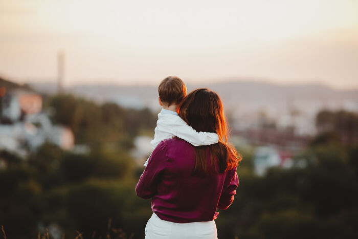 Woman holding child outdoors at sunset, reflecting on the reality of life after high school stardom.