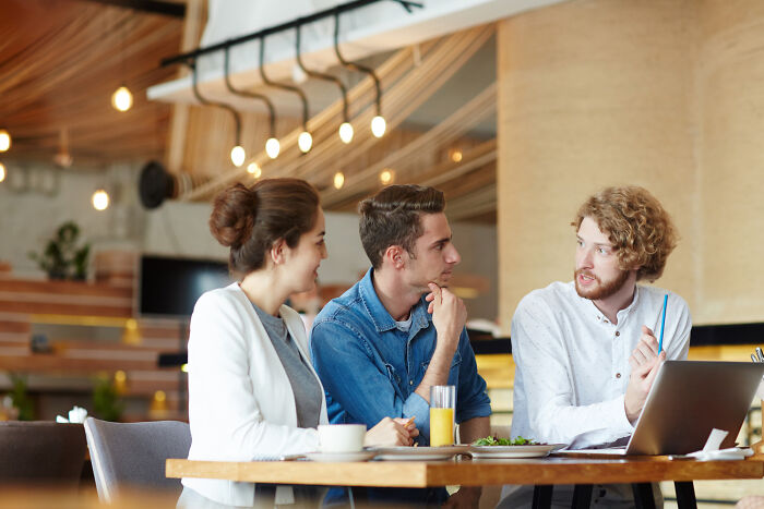 Three former high school stars discussing life after the glory days during a casual meeting with a laptop and drinks.