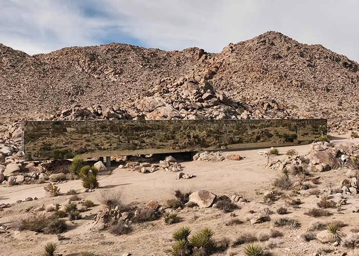 Mirrored invisible house blending into desert landscape with rocky hills, noted for Airbnb owners charging influencer fee. Mirrored invisible house blending into desert landscape with rocky hills, noted for Airbnb owners charging influencer fee.