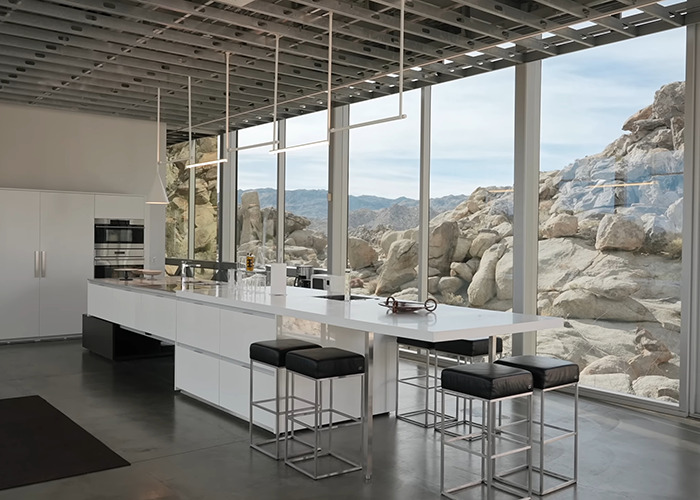 Modern kitchen interior with large windows showcasing rocky landscape at invisible house Airbnb owners charge influencer fee Modern kitchen interior with large windows showcasing rocky landscape at invisible house Airbnb owners charge influencer fee