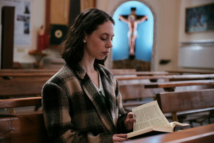 Woman reading a book alone in a church pew, reflecting on childish reasons ladies ditched a guy.