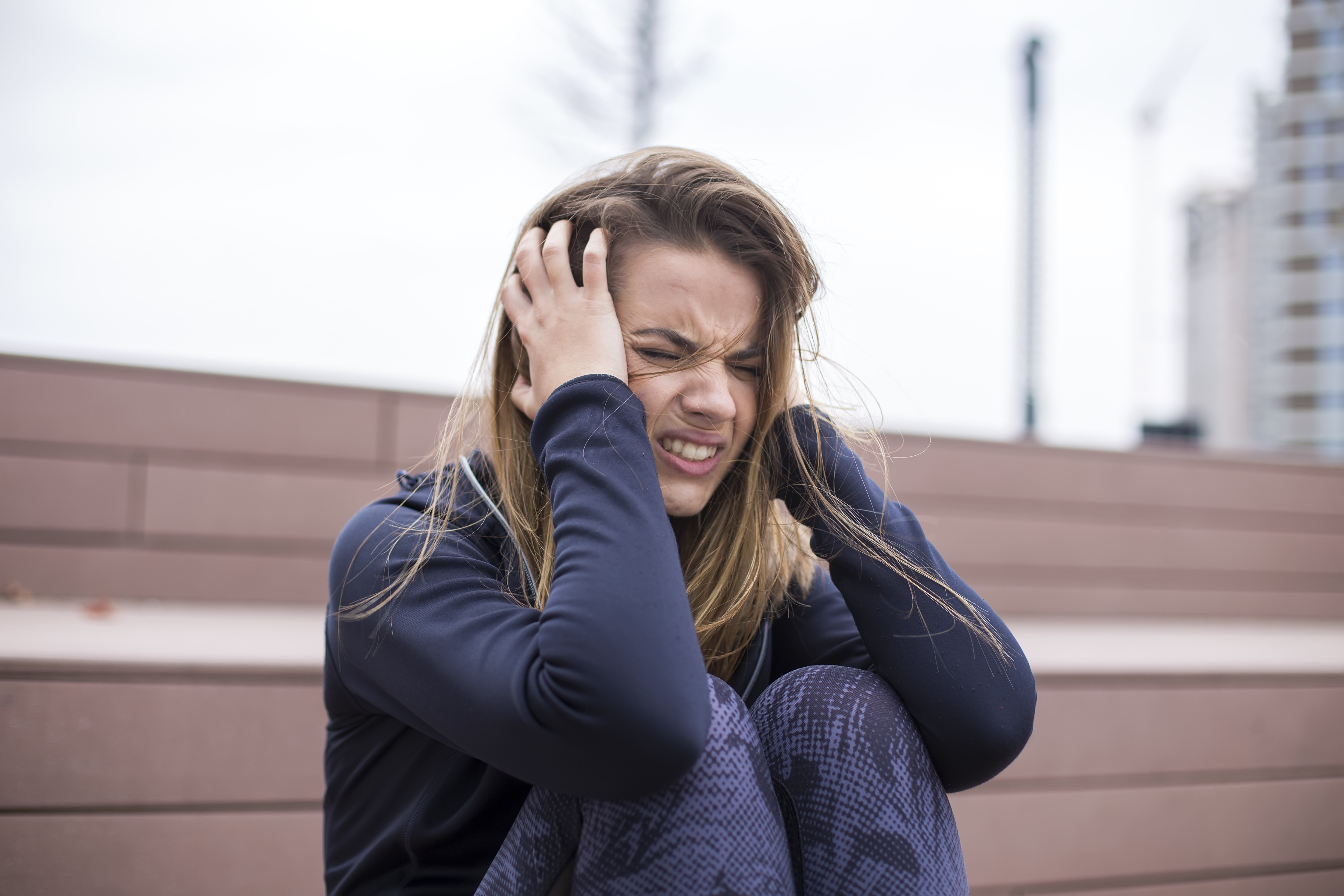 Young woman crying and distressed outdoors, expressing emotion related to demands and refusal in a backyard setting. Young woman crying and distressed outdoors, expressing emotion related to demands and refusal in a backyard setting.
