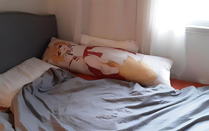 Anime pillow on a bed beside white pillows and gray blanket, reflecting MIL thinking son is in a throuple with wife. Anime pillow on a bed beside white pillows and gray blanket, reflecting MIL thinking son is in a throuple with wife.